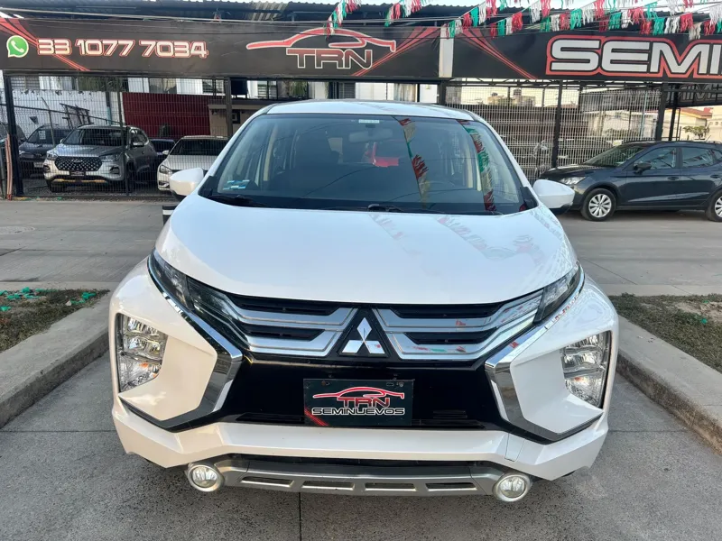 Mitsubishi Xpander blanca de frente en el lote de TRN Seminuevos, con el rótulo y el WhatsApp del negocio al fondo